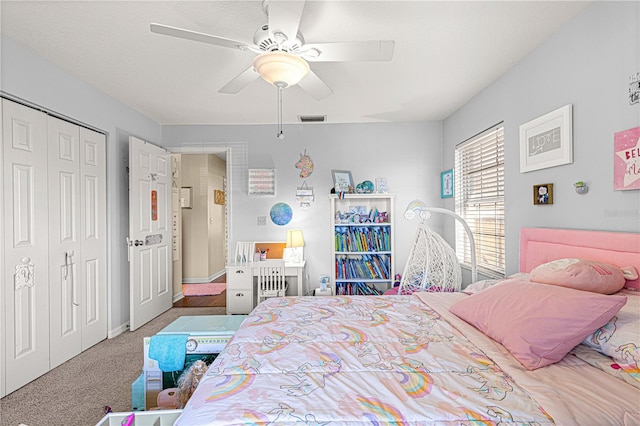 carpeted bedroom with ceiling fan, a closet, and a textured ceiling