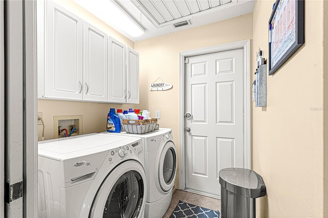 laundry area with washer and dryer, light tile patterned floors, and cabinets