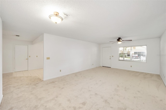 interior space with a textured ceiling, light colored carpet, and ceiling fan