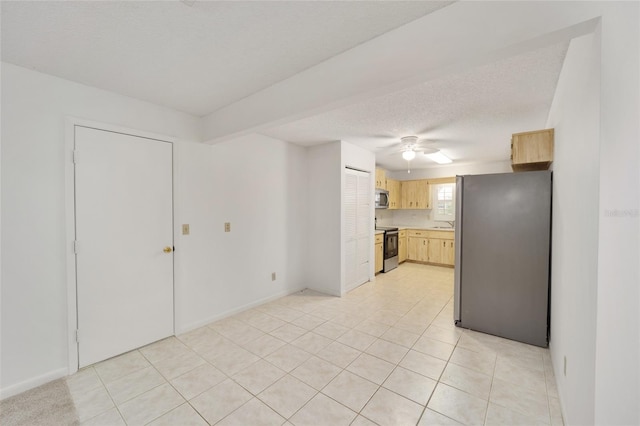 kitchen with a textured ceiling, light brown cabinets, light tile patterned flooring, and stainless steel appliances