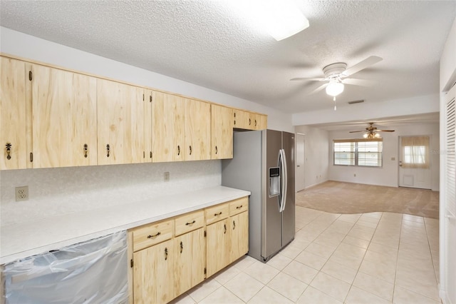 kitchen featuring a textured ceiling, light tile patterned flooring, stainless steel appliances, and light brown cabinetry