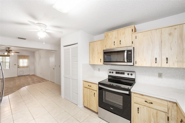 kitchen featuring a textured ceiling, light brown cabinets, light tile patterned flooring, and stainless steel appliances