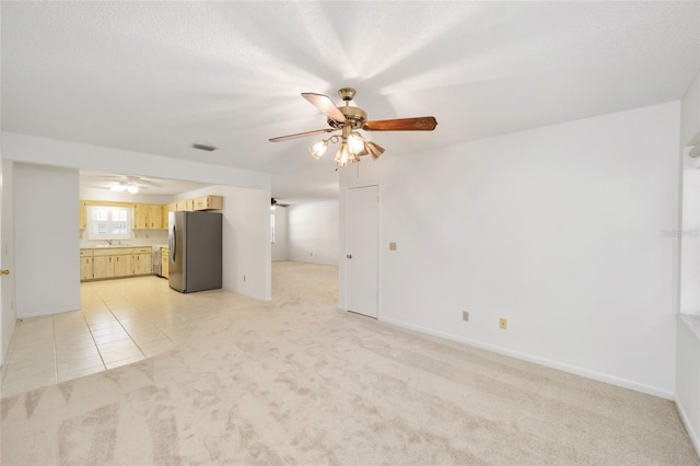 unfurnished living room featuring a textured ceiling, light colored carpet, and ceiling fan