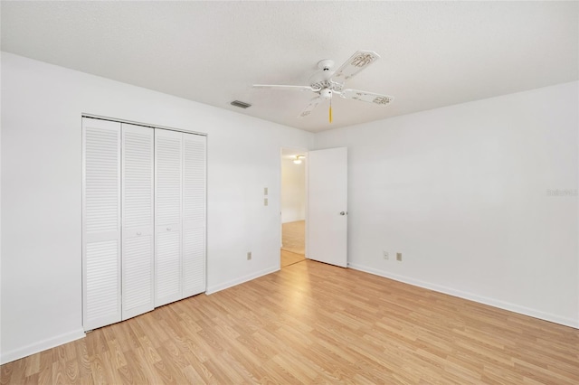 unfurnished bedroom featuring ceiling fan, light hardwood / wood-style floors, and a closet