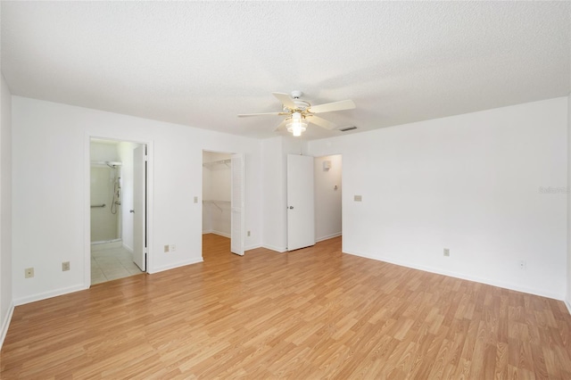 empty room featuring a textured ceiling, light wood-type flooring, and ceiling fan