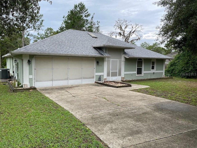 view of front of house featuring central AC unit, a garage, and a front yard