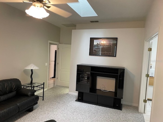 carpeted living room with ceiling fan and a skylight