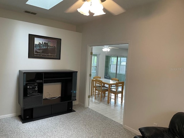 carpeted living room featuring a skylight and ceiling fan