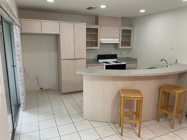 kitchen with a kitchen bar, sink, light brown cabinets, white electric stove, and light tile patterned flooring