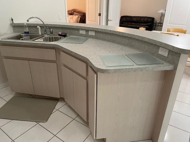 kitchen with tile patterned flooring, kitchen peninsula, and sink