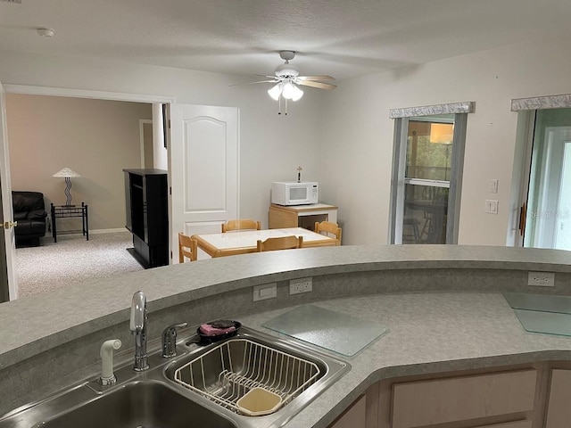 kitchen with ceiling fan, carpet floors, and sink