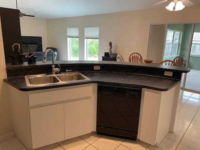 kitchen with white cabinetry, sink, black dishwasher, a fireplace, and light tile patterned floors