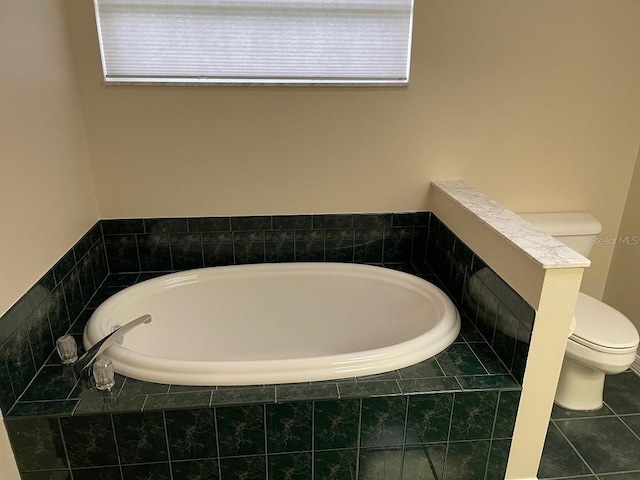 bathroom featuring tile patterned floors, toilet, and tiled tub