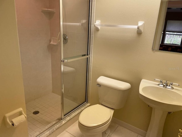 bathroom featuring tile patterned floors, toilet, a shower with shower door, and sink