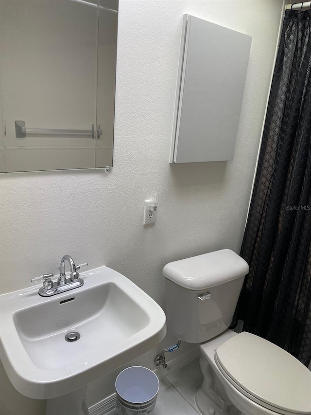 bathroom featuring tile patterned floors, curtained shower, sink, and toilet