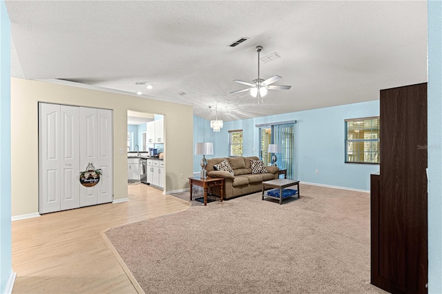 living room featuring a textured ceiling, light hardwood / wood-style floors, ceiling fan, and sink