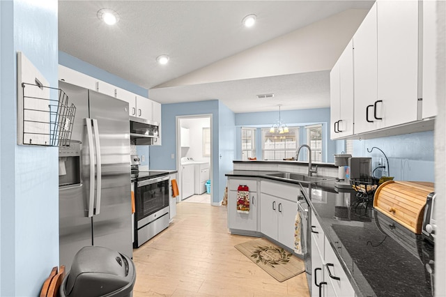 kitchen with pendant lighting, lofted ceiling, sink, white cabinetry, and stainless steel appliances