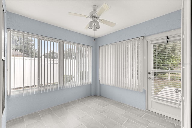 unfurnished sunroom featuring ceiling fan