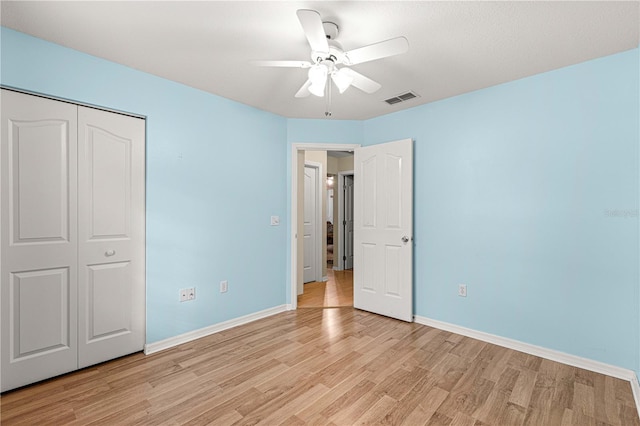 unfurnished bedroom featuring ceiling fan, a closet, and light wood-type flooring