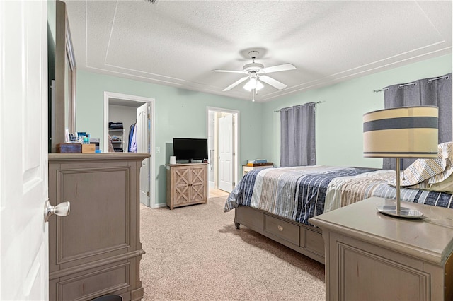 bedroom featuring light carpet, a textured ceiling, ceiling fan, and connected bathroom