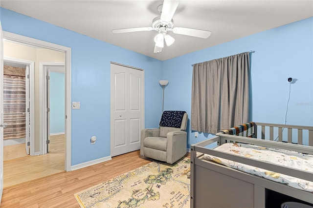 bedroom with hardwood / wood-style floors, ceiling fan, a crib, and a closet