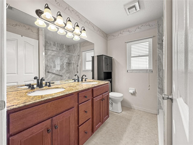 bathroom with double vanity, toilet, a sink, and a shower