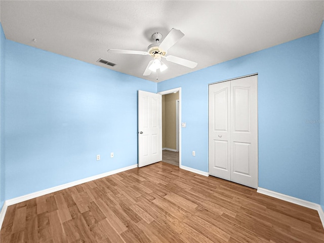 unfurnished bedroom featuring visible vents, a closet, baseboards, ceiling fan, and light wood-type flooring