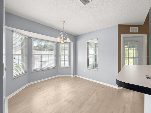 unfurnished dining area featuring visible vents, wood finished floors, and an inviting chandelier