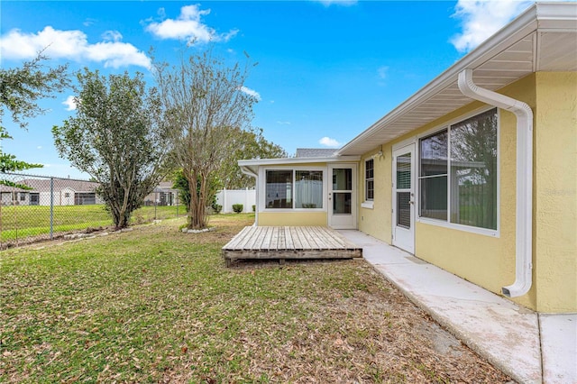 view of yard featuring a deck, a sunroom, and fence