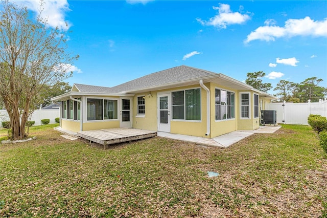 back of house featuring a wooden deck, a sunroom, a fenced backyard, central AC unit, and a lawn