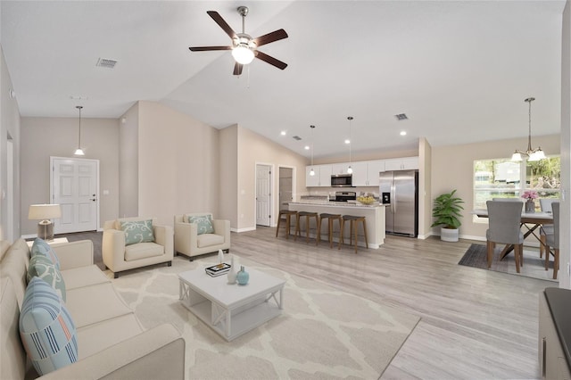 living room featuring ceiling fan with notable chandelier, light hardwood / wood-style floors, and high vaulted ceiling