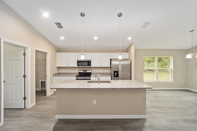 kitchen featuring appliances with stainless steel finishes, light wood-type flooring, light stone counters, a kitchen island with sink, and white cabinetry