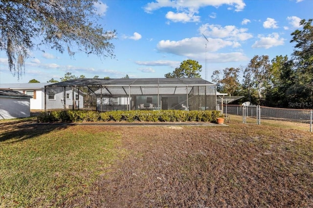 rear view of property featuring a lawn and glass enclosure