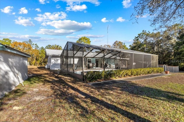 rear view of property with glass enclosure and a yard