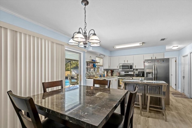 dining room featuring a chandelier, sink, light hardwood / wood-style floors, and a textured ceiling