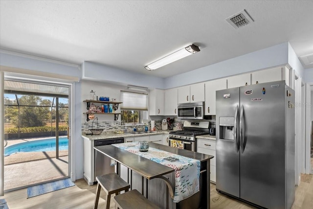 kitchen featuring white cabinets, appliances with stainless steel finishes, light hardwood / wood-style flooring, and sink