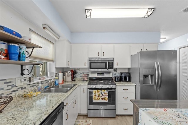 kitchen featuring appliances with stainless steel finishes, light wood-type flooring, light stone counters, sink, and white cabinets