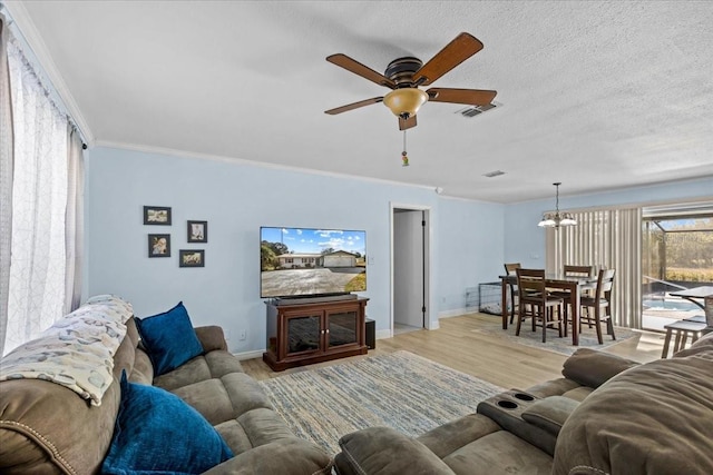 living room featuring ceiling fan with notable chandelier, a textured ceiling, light wood-type flooring, and ornamental molding