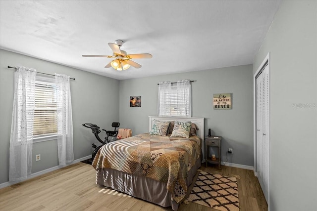 bedroom with a closet, light hardwood / wood-style flooring, and multiple windows