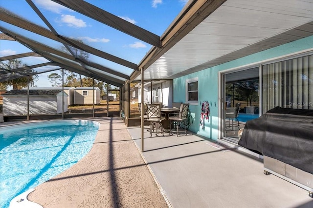 view of swimming pool featuring glass enclosure, a grill, a patio area, and a storage shed