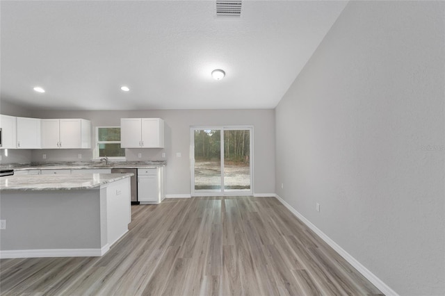 kitchen featuring light stone countertops, white cabinets, dishwasher, sink, and light wood-type flooring