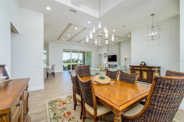 dining space featuring light wood-type flooring, a fireplace, and a chandelier