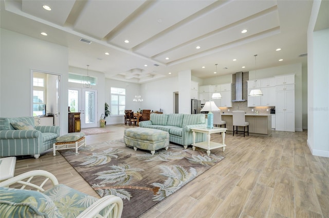 living room featuring light hardwood / wood-style flooring, french doors, and a notable chandelier