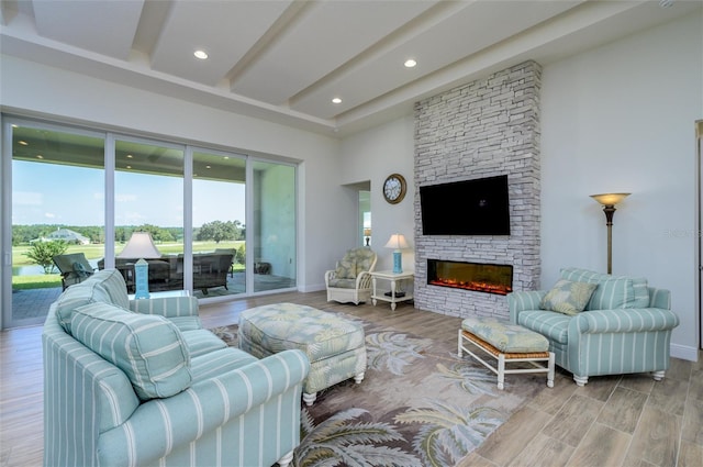 living room with beamed ceiling, hardwood / wood-style floors, and a stone fireplace