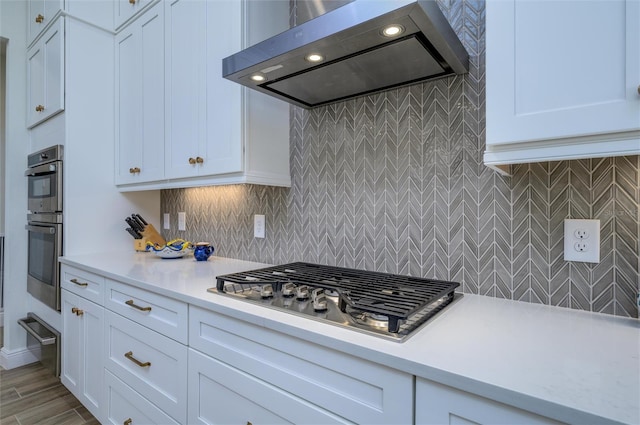 kitchen featuring light hardwood / wood-style flooring, range hood, backsplash, white cabinets, and appliances with stainless steel finishes