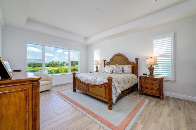 bedroom featuring light hardwood / wood-style floors, a raised ceiling, and crown molding