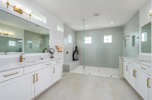 bathroom with tile patterned flooring, vanity, a tile shower, and tile walls