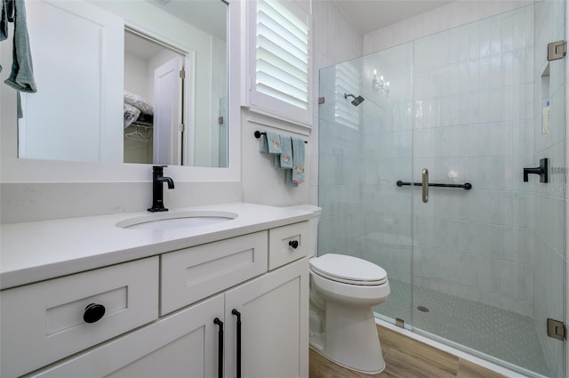 bathroom with hardwood / wood-style floors, vanity, toilet, and walk in shower