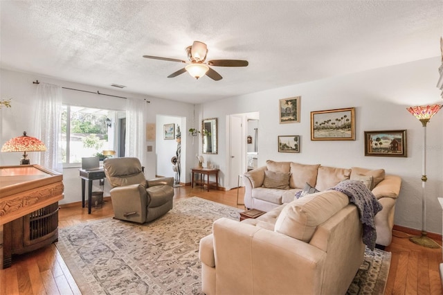 living room featuring ceiling fan, a textured ceiling, and hardwood / wood-style flooring