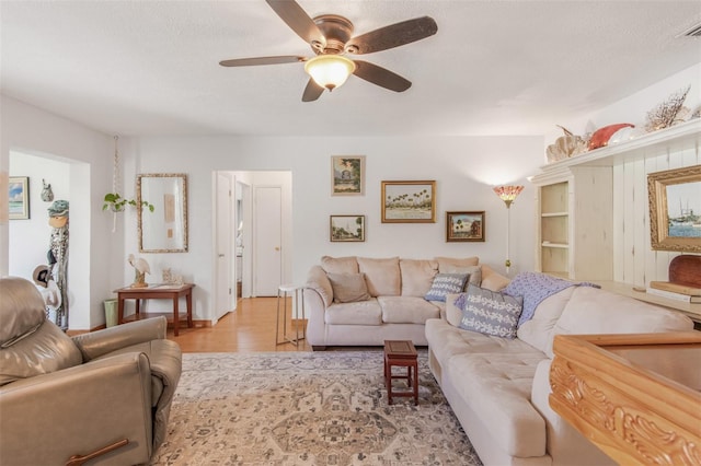 living room featuring a textured ceiling, light hardwood / wood-style flooring, and ceiling fan